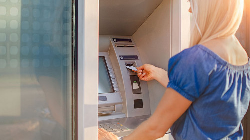Young woman withdrawing money from credit card at ATM machine