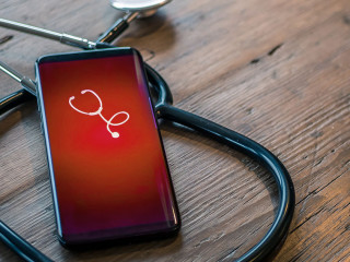 Mobile phone with healthcare app on wood table with stethoscope