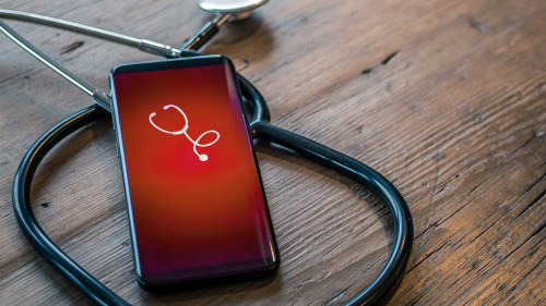 Mobile phone with healthcare app on wood table with stethoscope