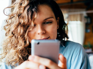 Close-up portrait of young woman texting on smart phone