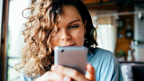 Close-up portrait of young woman texting on smart phone