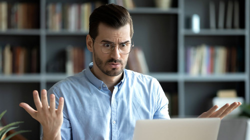 Unhappy young man work on laptop confused by gadget problems