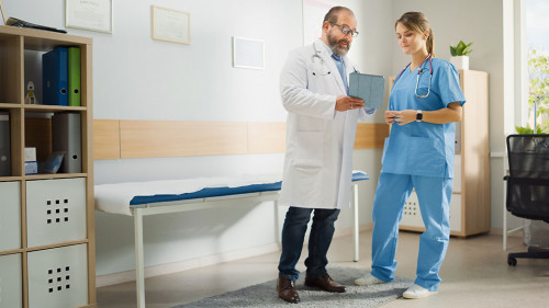 Doctor's Office: Physician Stands, Talks With Professional Head