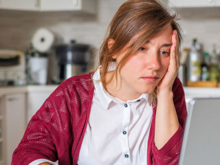 Stressed woman sitting at home and checking unpaid bills