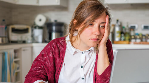 Stressed woman sitting at home and checking unpaid bills