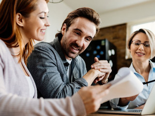 Bellow view of happy couple having a meeting with insurance agent.