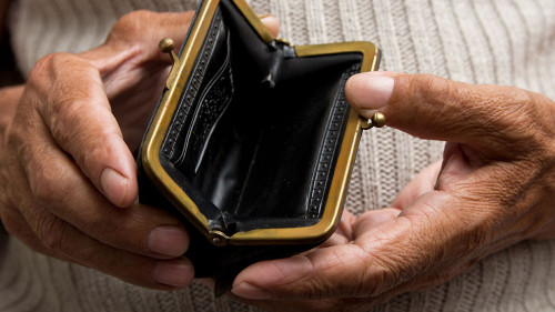 An elderly man holds an empty purse. The concept of poverty in r