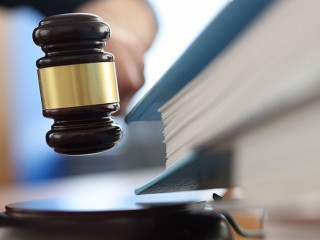 Wooden gavel for judge on table next to folder with documents.