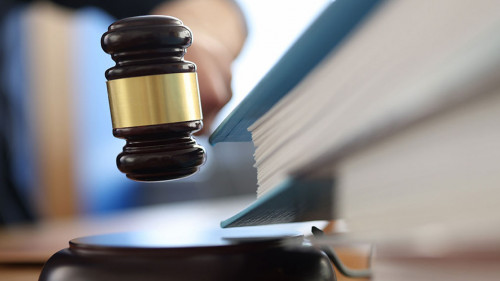 Wooden gavel for judge on table next to folder with documents.