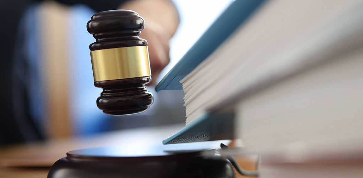 Wooden gavel for judge on table next to folder with documents.