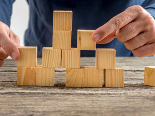 Man Assembling Wooden Cubes on Table