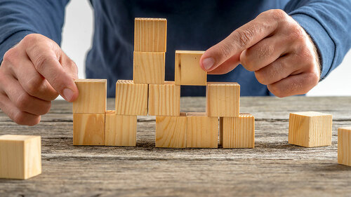 Man Assembling Wooden Cubes on Table