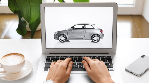 Woman using laptop to buy car at table indoors, closeup