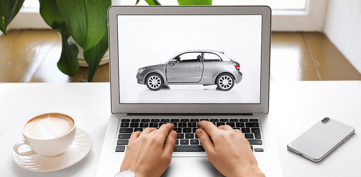 Woman using laptop to buy car at table indoors, closeup