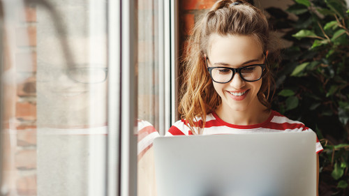 Calm young woman working on laptop at home
