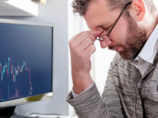 Depressed investor analyzing crisis stock market with graph on s