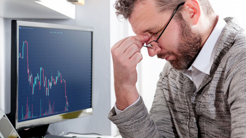 Depressed investor analyzing crisis stock market with graph on s