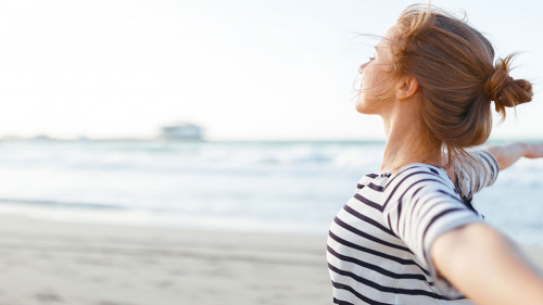 happy woman enjoying freedom with open hands on sea
