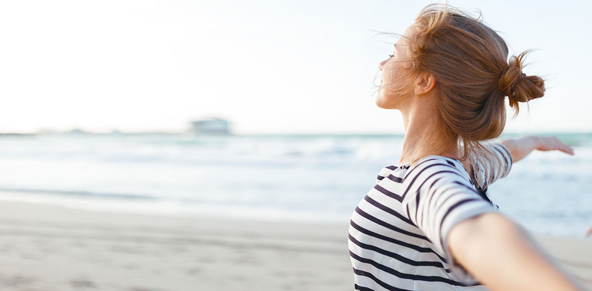 happy woman enjoying freedom with open hands on sea