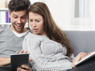 Junges Pärchen schaut erstaunt auf ein Tablet Computer