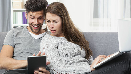 Junges Pärchen schaut erstaunt auf ein Tablet Computer