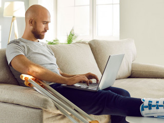 Unwell man with broken leg work on computer