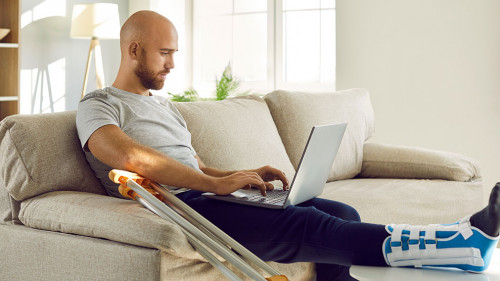 Unwell man with broken leg work on computer