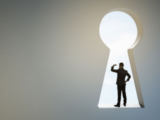 Back view of business man standing in abstract key hole opening in concrete wall with mock up place. Solution and success concept.