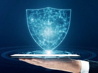 Close up of businessman hand holding tablet with glowing polygonal shield on blue background. Secure and safety concept.