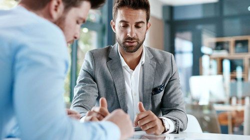 Digitizing a financial discussion. Cropped shot of two young businessmen using a digital tablet while going through paperwork together in a modern office.