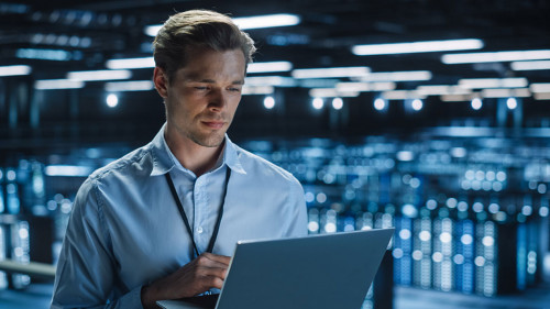 Handsome Smiling IT Specialist Using Laptop Computer in Data Cen