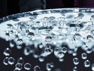 Shower Head with Water Stream on Black Background