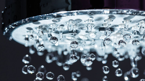 Shower Head with Water Stream on Black Background