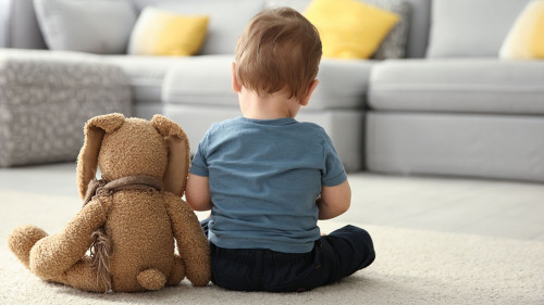 Little boy with toy sitting on floor in living room. Autism conc