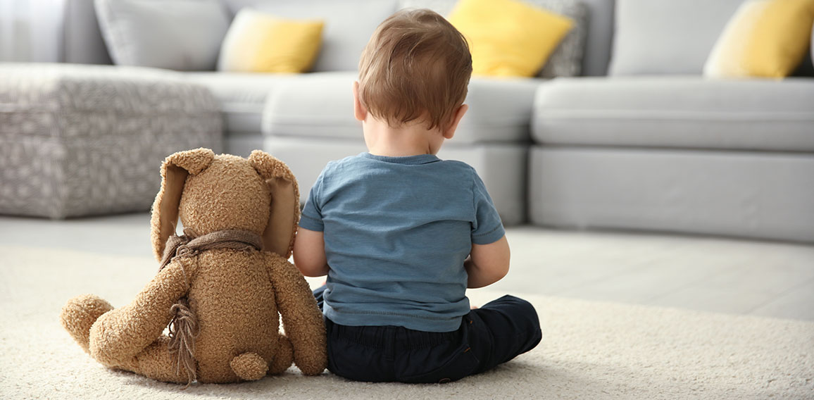 Little boy with toy sitting on floor in living room. Autism conc