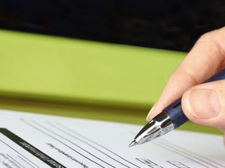 Hand with Pen Signing Form by Green Folder