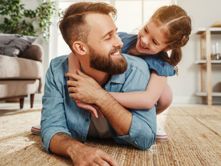 Cheerful father and daughter having fun and hugging in living room