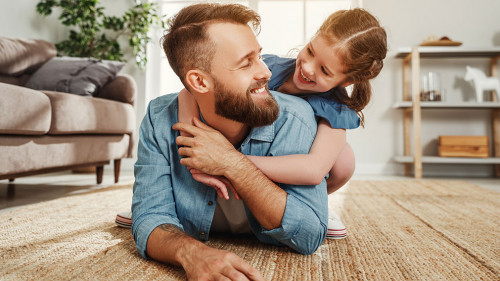 Cheerful father and daughter having fun and hugging in living room
