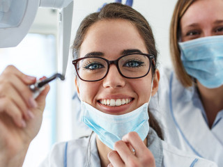 Two female dentist in dental office examining patient teeth.Came