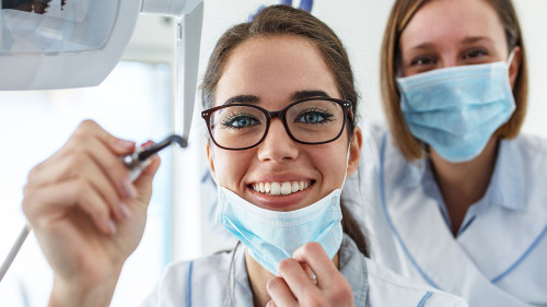 Two female dentist in dental office examining patient teeth.Came