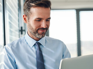 Handsome businessman in modern office looking on laptop computer