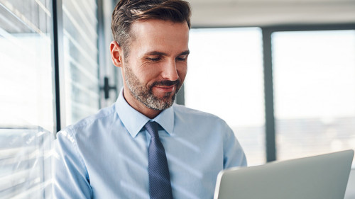 Handsome businessman in modern office looking on laptop computer