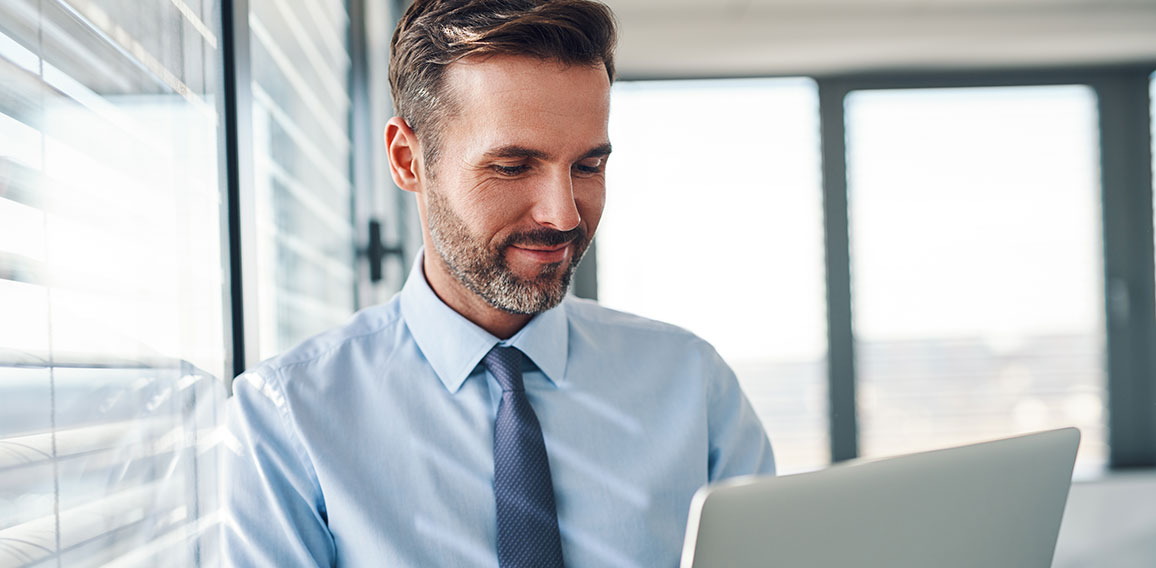 Handsome businessman in modern office looking on laptop computer