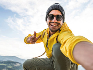 Young hiker man taking selfie portrait on the top of mountain -