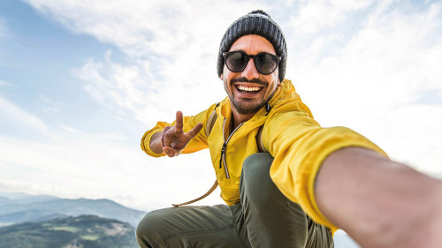Young hiker man taking selfie portrait on the top of mountain -