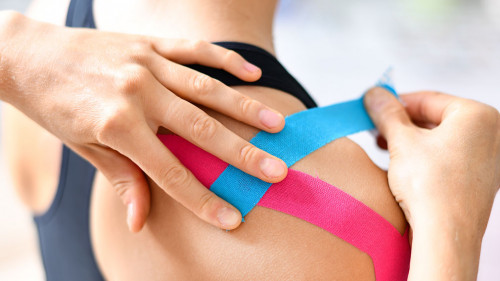 Kinesiology taping treatment with blue and pink tape on athlete