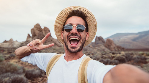 Handsome hiker taking a selfie hiking a mountain using his smart