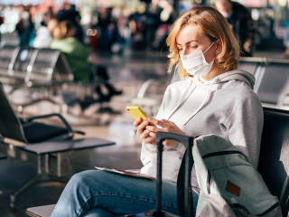 A European woman in a protective medical mask on her face sits a