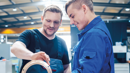 Master discussing a workpiece with his apprentice or trainee