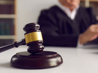 Close-up of wooden gavel placed on sound block on judge's table during court hearing
